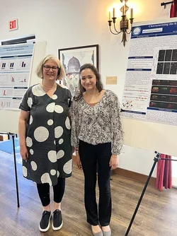 two women in front of a scientific poster