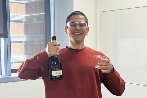 man holding up a bottle of sparkling wine
