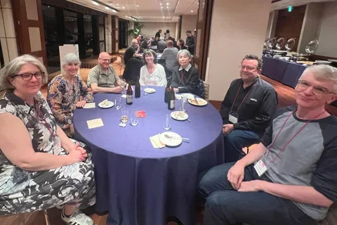 a group of seven scientists sitting around a table