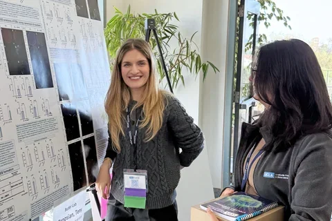 Smiling woman presenting a scientific poster at a meeting