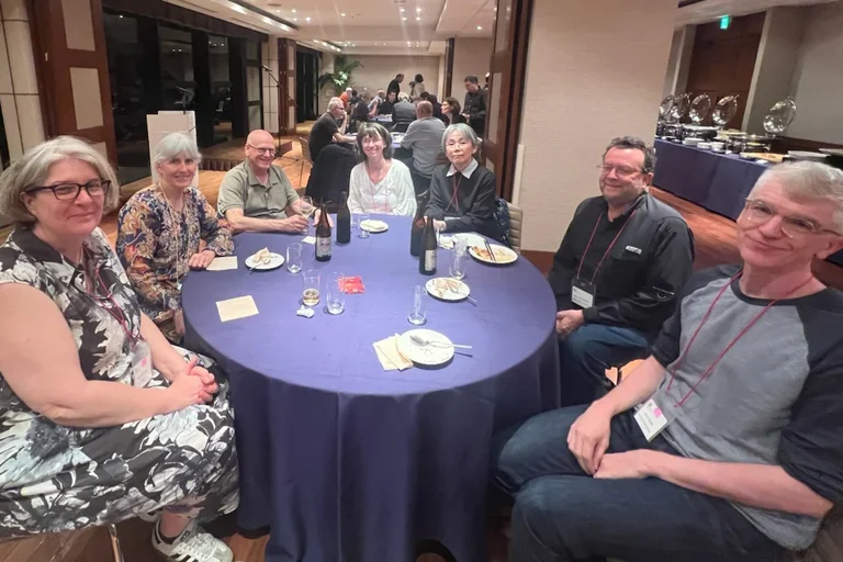 a group of seven scientists sitting around a table