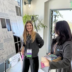 Smiling woman presenting a scientific poster at a meeting